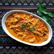 a bowl of panang curry pork with makrut lime leaves on the side.