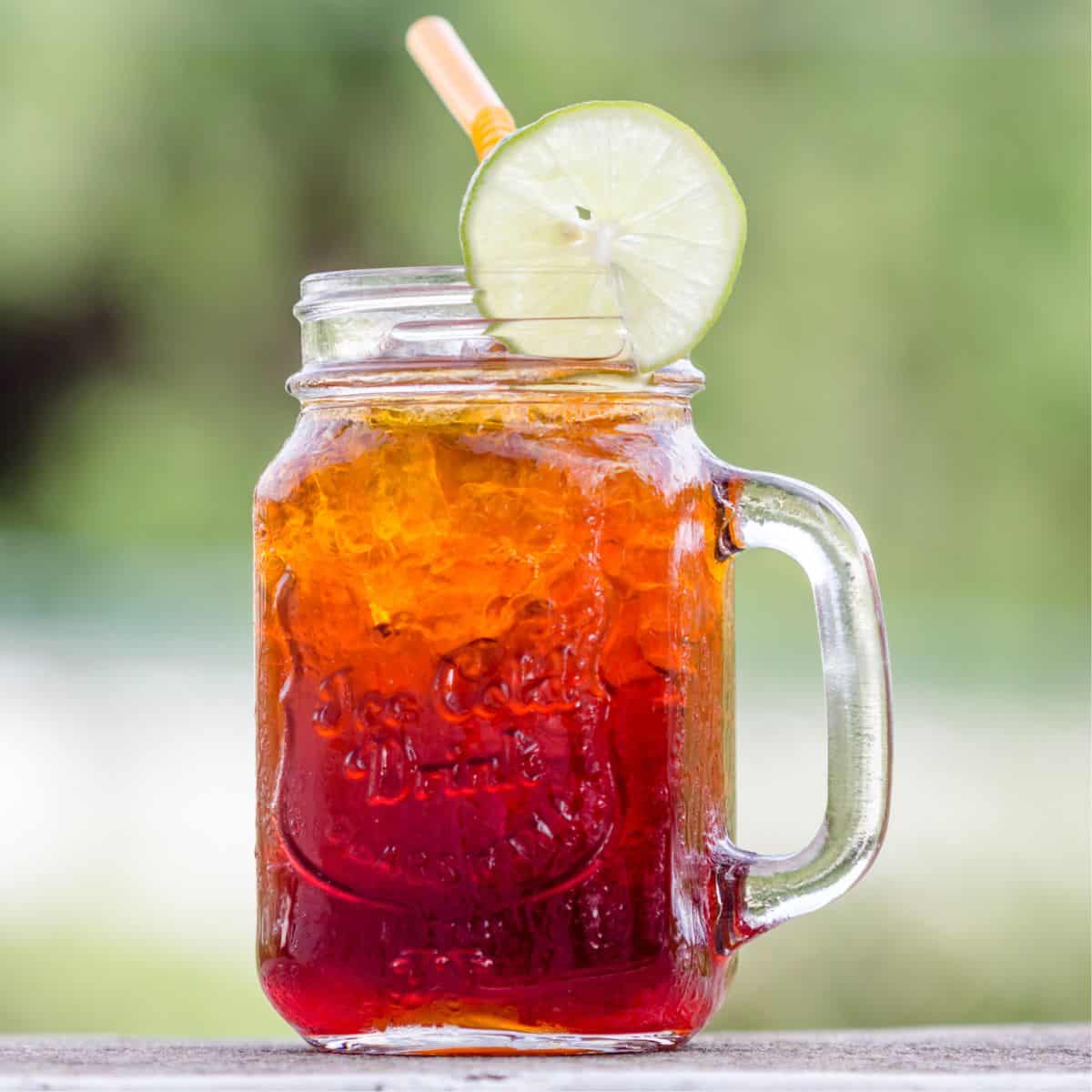 a glass mug of thai lime tea with a lime garnish