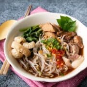 A bowl of boat noodles on pink napkin with text overlay "authentic thai boat noodles" and "hotthaikitchen.com".