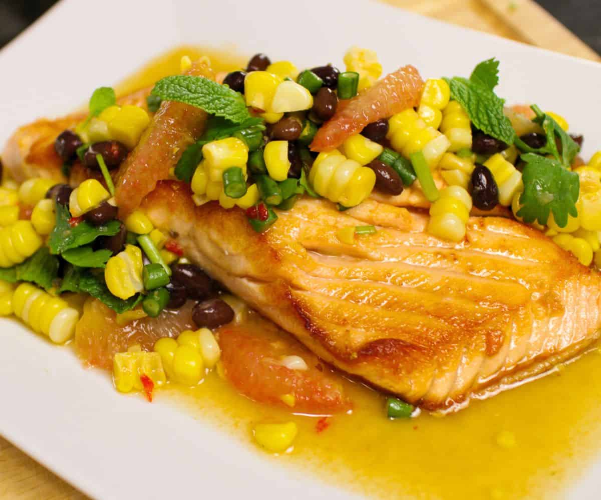 a plate of seared salmon with corn and bean salsa