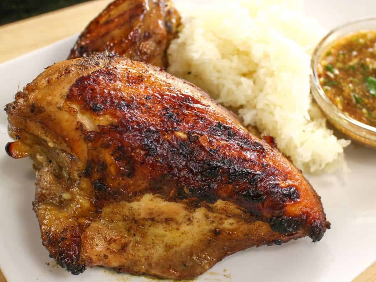 A plate of grilled chicken breast with a side of sticky rice