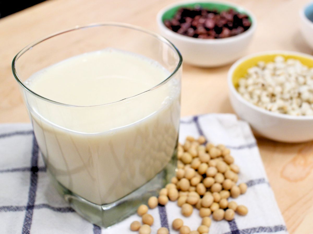 a glass of soy milk with bowls of beans and job's tears in the back