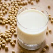 a glass of soymilk with soy beans on the table