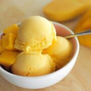 a bowl of mango ice cream with mangoes on the side