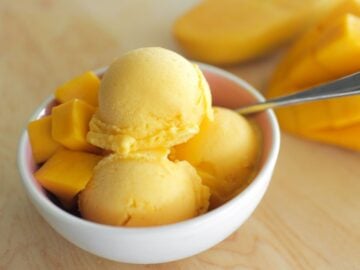 a bowl of mango ice cream with mangoes on the side