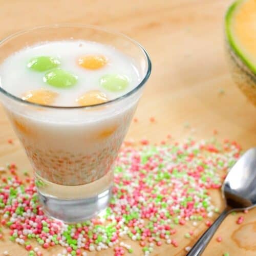 tapioca melon coconut dessert in a glass cup with tapioca pearls and a cantaloupe in the background