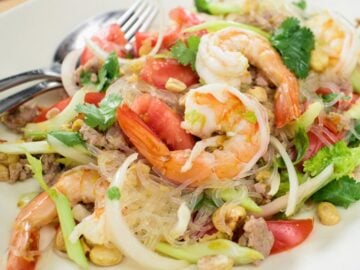 a plate of glass noodle salad with shrimp on top