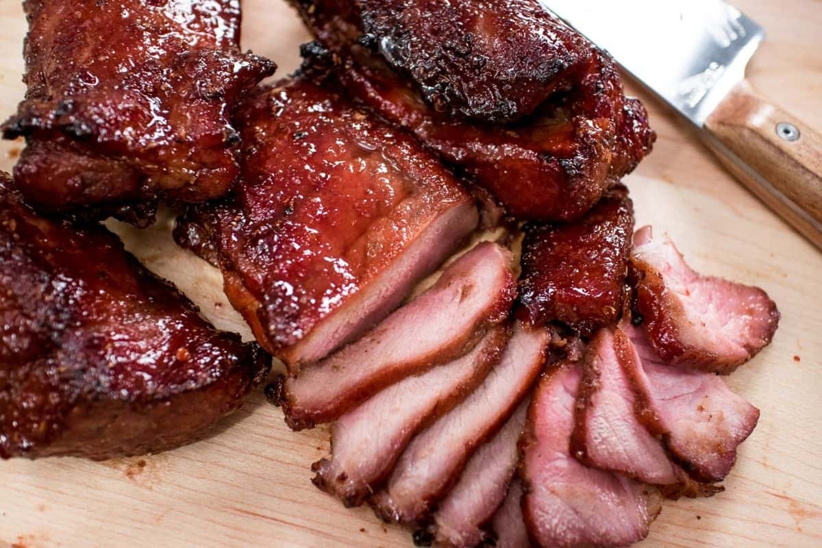 Chinese barbecue pork on a cutting board with several sliced pieces