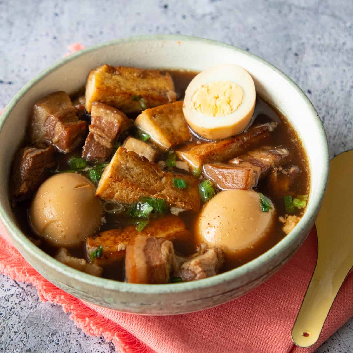 a bowl of thai five spice pork belly and egg stew on an orange napkin