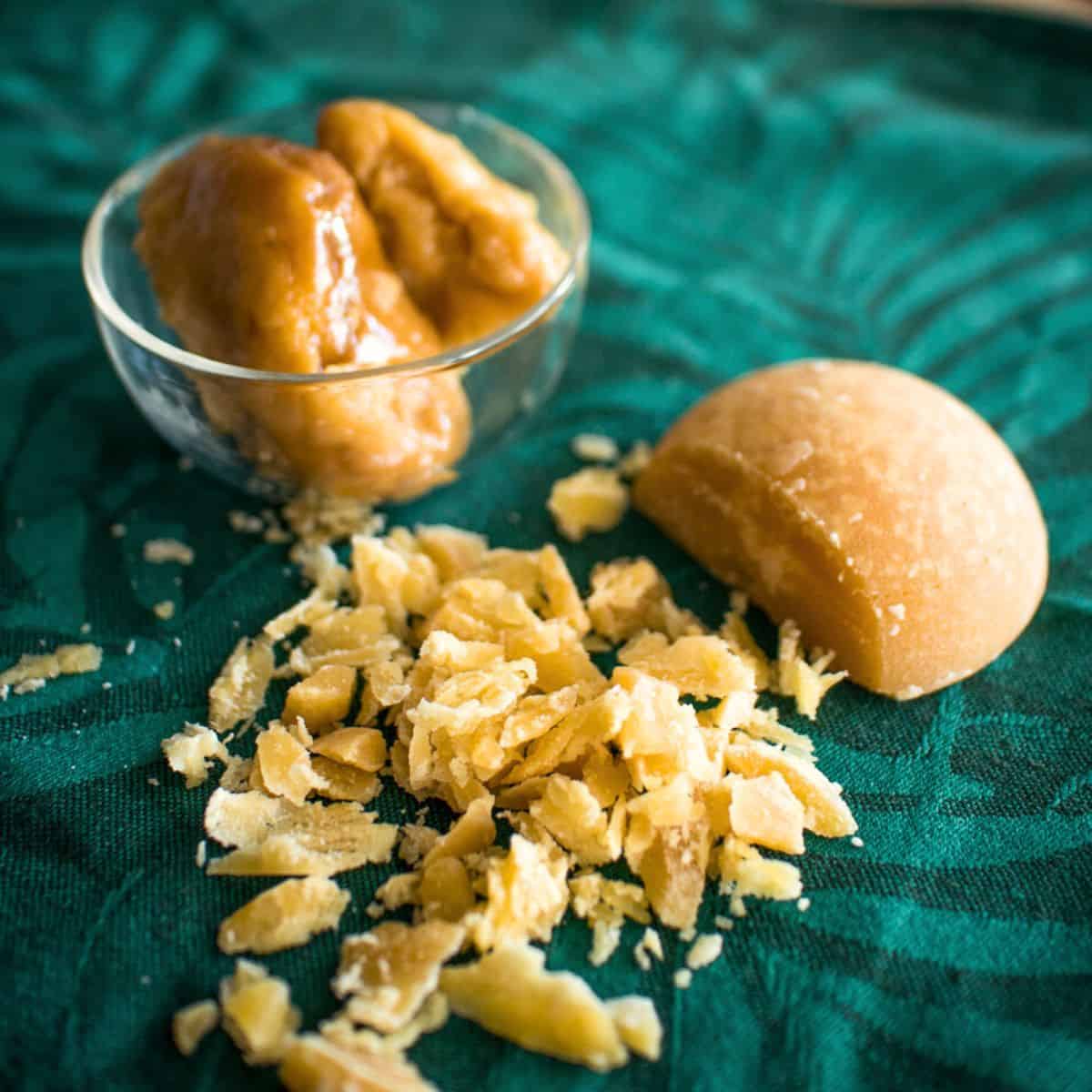 palm sugar on green cloth partially chopped, and some more palm sugar in a glass cup