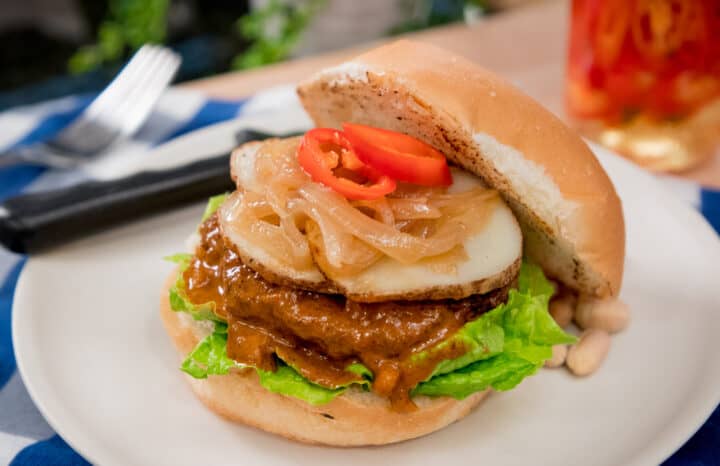 A plate of massaman burger with potatoes, onions and chilies.
