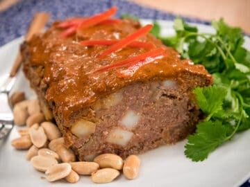 Massaman meatloaf on a plate with peanuts and cilantro garnish.