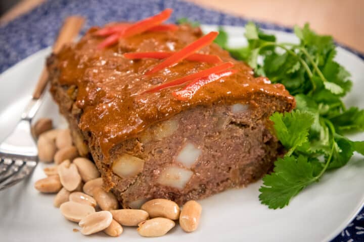 Massaman meatloaf on a plate with peanuts and cilantro garnish.