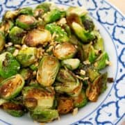 A plate of pan seared brussel sprouts with fried garlic on top.