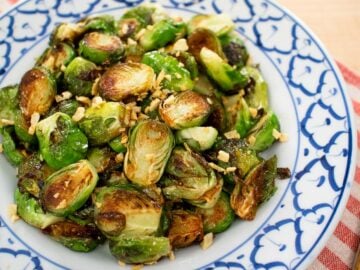 A plate of pan seared brussel sprouts with fried garlic on top.