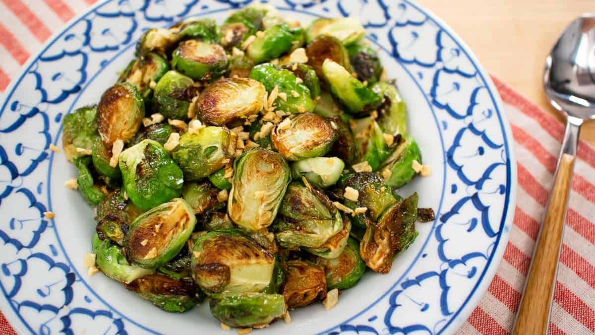 A plate of pan seared brussel sprouts with fried garlic on top.