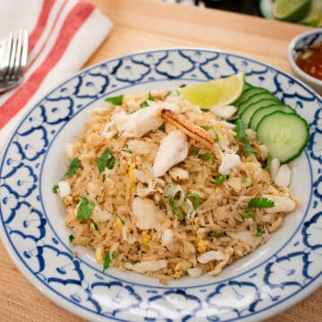A plate of fried rice with crab, cucumber and lime.