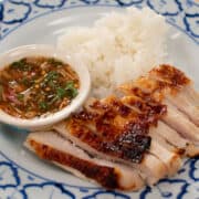 A plate of roasted turkey breast slices, sticky rice, and a bowl of Thai dipping sauce
