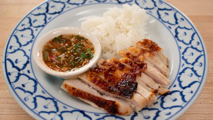 A plate of roasted turkey breast slices, sticky rice, and a bowl of Thai dipping sauce