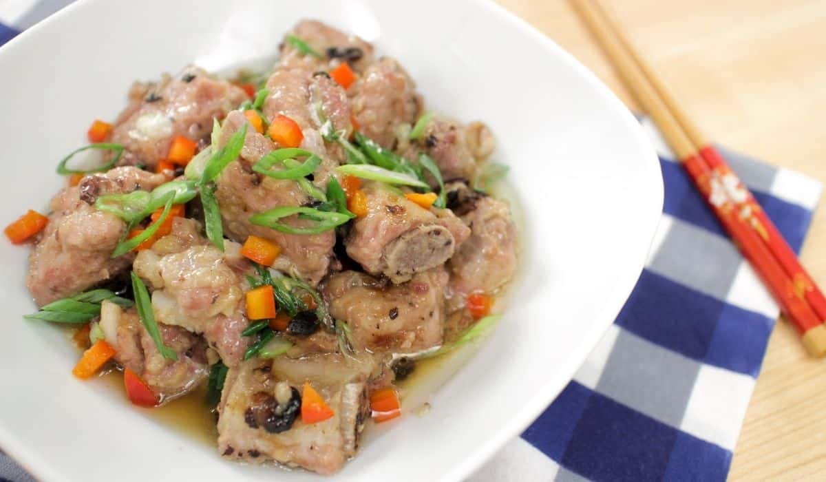 A bowl of steamed spare ribs with green onions and bell pepper garnish