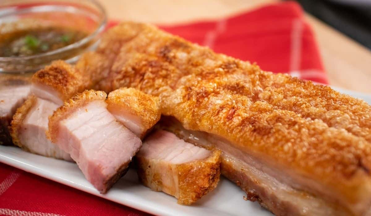 A plate of crispy pork belly, one big piece and a few cut pieces