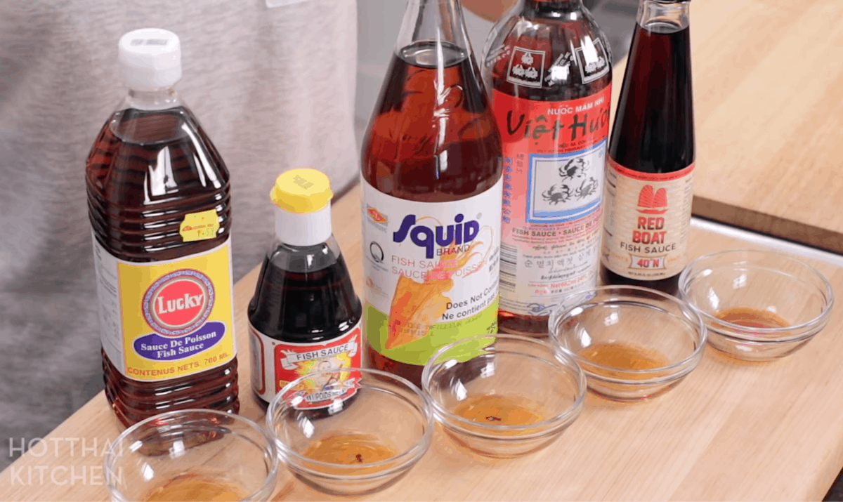 A line up of 5 different brands of fish sauce: Lucky, Golden Boy, Squid, 3 Crabs, and Red Boat