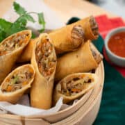 Crispy spring rolls cut in half in a steamer basket