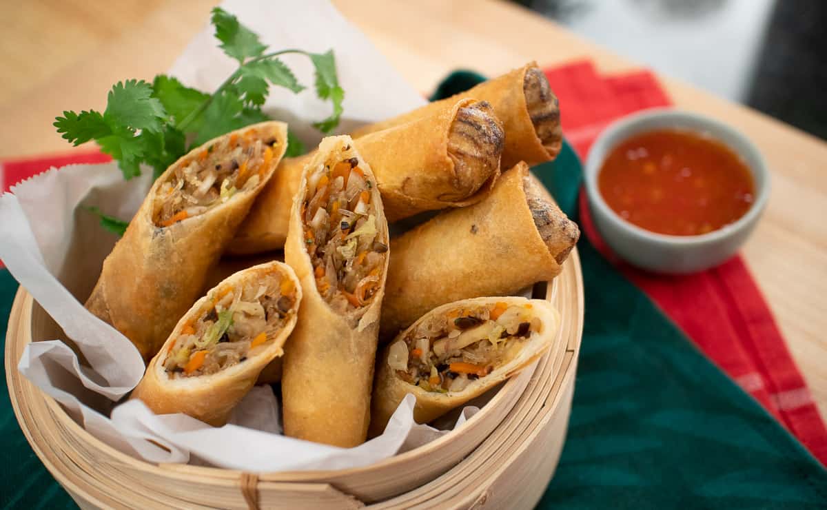 Crispy spring rolls cut in half in a steamer basket