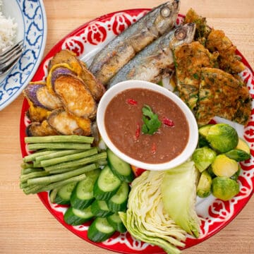 A platter of shrimp a step surrounded by mackerel, omelette, and veggies