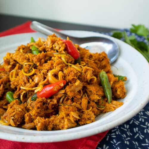 A plate of tuna stir fried in red curry with red and green chilies.