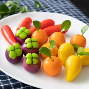 A plate of look choop made into oranges, mangoes, mangosteens, and chilies