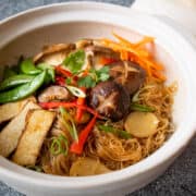 Glass noodles in clay pot topped with tofu, mushrooms, sugar snap peas, red pepper and carrots