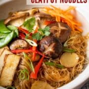 Glass noodles in a clay pot topped with veggies and tofu. With text overlay "vegan claypot noodles".