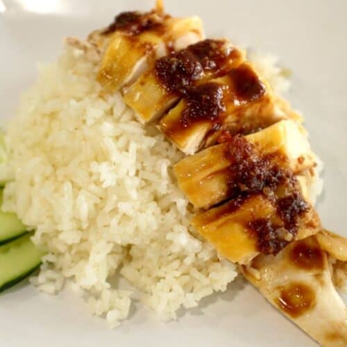 A plate of Hainanese chicken rice with a side of cucumber