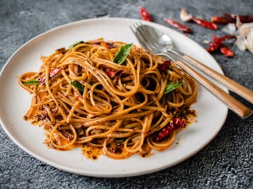 A plate of chili garlic noodles with thai basil