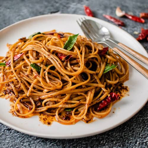 A plate of chili garlic noodles with thai basil