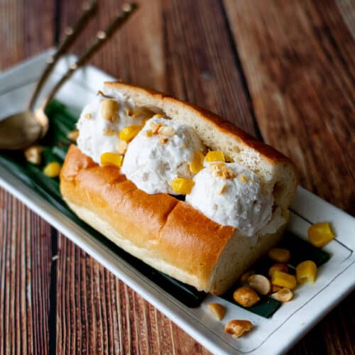 3 scoops of coconut ice cream in a hotdog bun, topped with peanuts and corn.