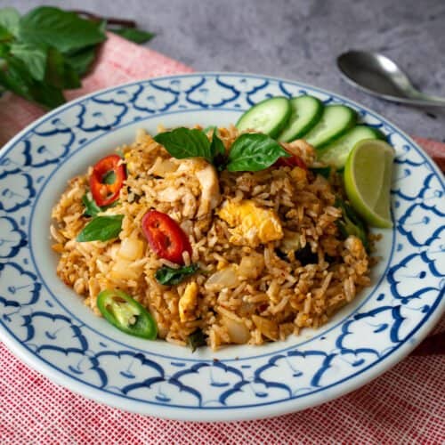 A plate of triple chili fried rice with cucumber slices and a lime wedge