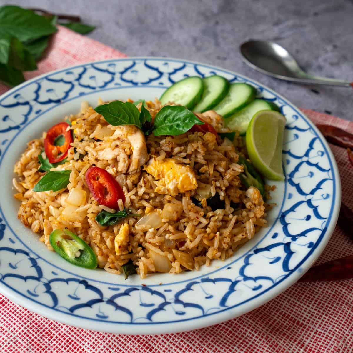 A plate of triple chili fried rice with cucumber slices and a lime wedge