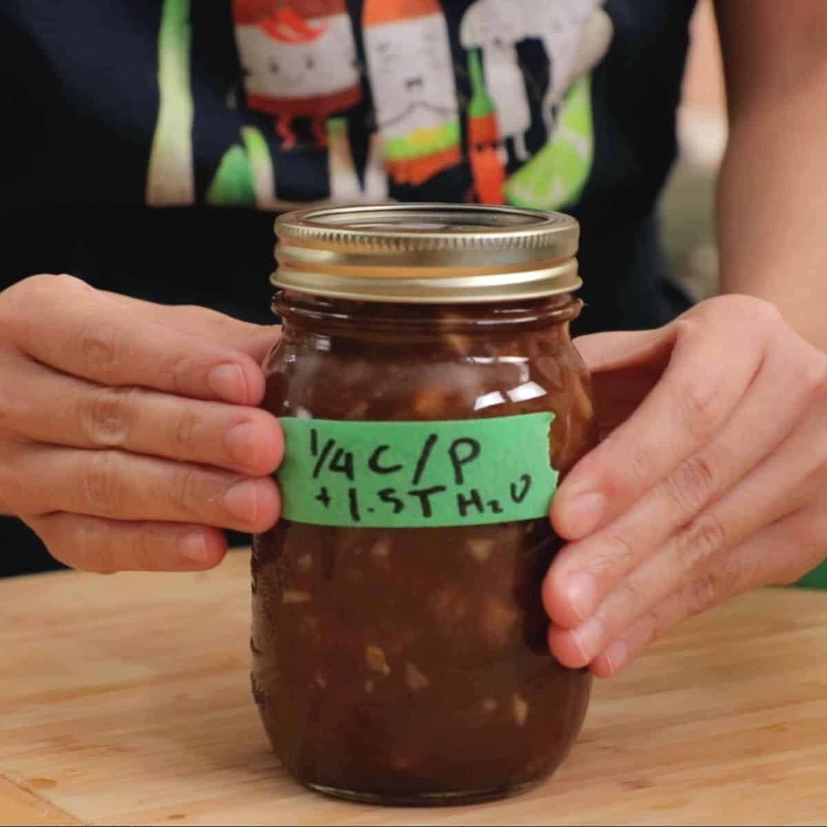 A mason jar of pad thai sauce with masking tape on it labelled "¼ c/p + 1.5 T H2O"