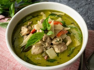 a bowl of thai green curry with basil garnish