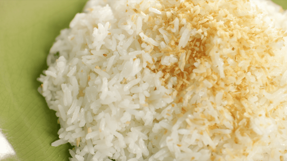 a plate of coconut rice with toasted coconut on top
