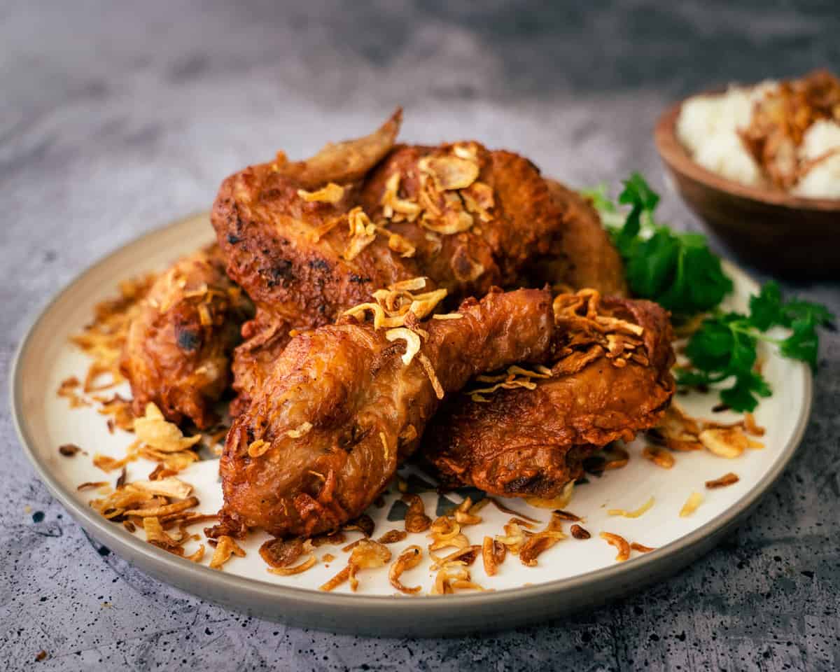 a plate of thai fried chicken with fried shallots