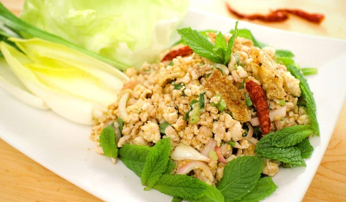 Laab gai on a plate with mint and fresh veggies