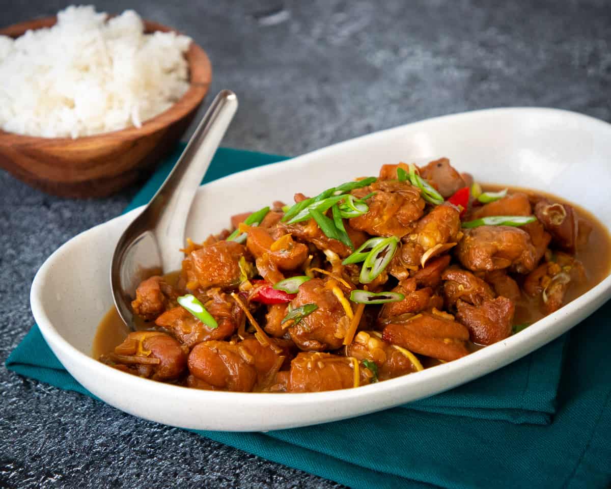 a plate of caramel chicken with a bowl of rice on the side