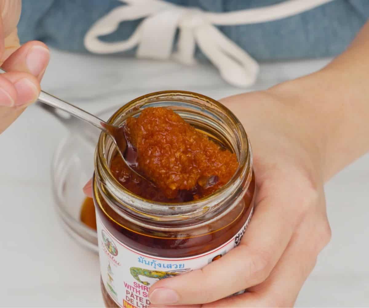 A spoon scooping shrimp paste in oil our of the jar