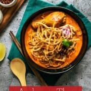 A bowl of khao soi chicken with condiments on the side with text overlay "authentic thai khao soi"