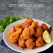 A plate of spicy wings zabb with a lime wedge, with text "Spicy & Zingy Thai wings KFC Wingz Zabb"