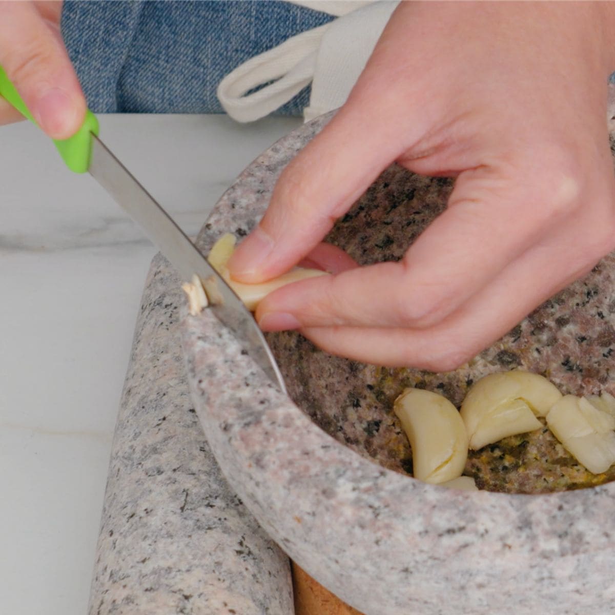 Garlic being sliced on the edge of mortar