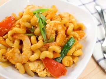 a plate of pad macaroni with shrimp and tomatoes